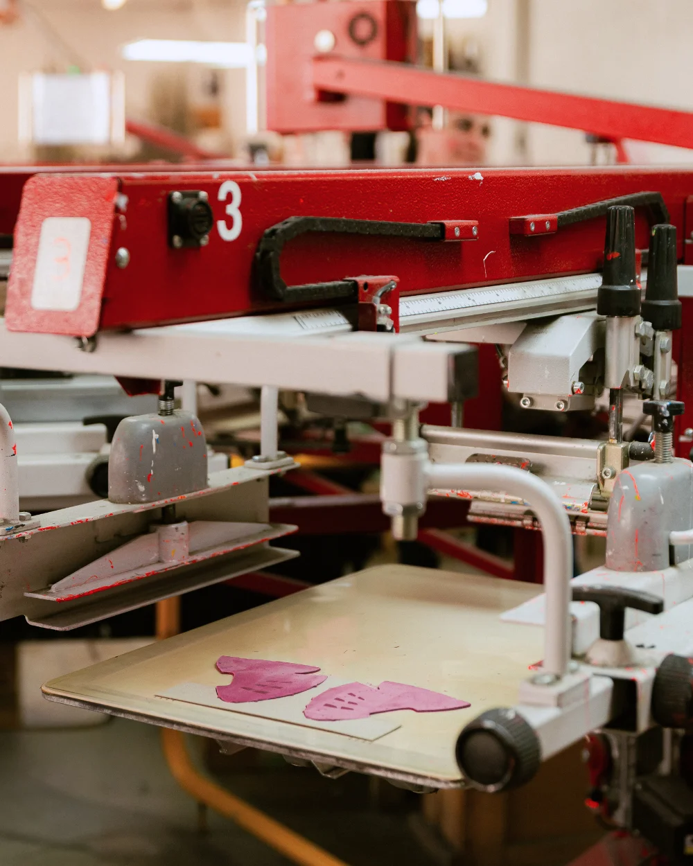 Mașină serigrafie industrială cu piese roz pe platou - Antel Print