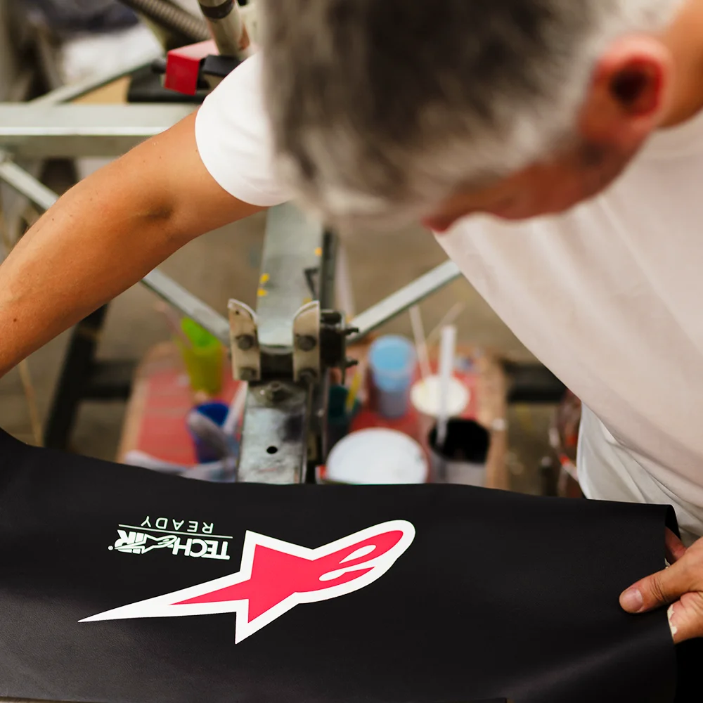 Operator verificând manual material serigrafiat logo Alpinestars - Antel Print